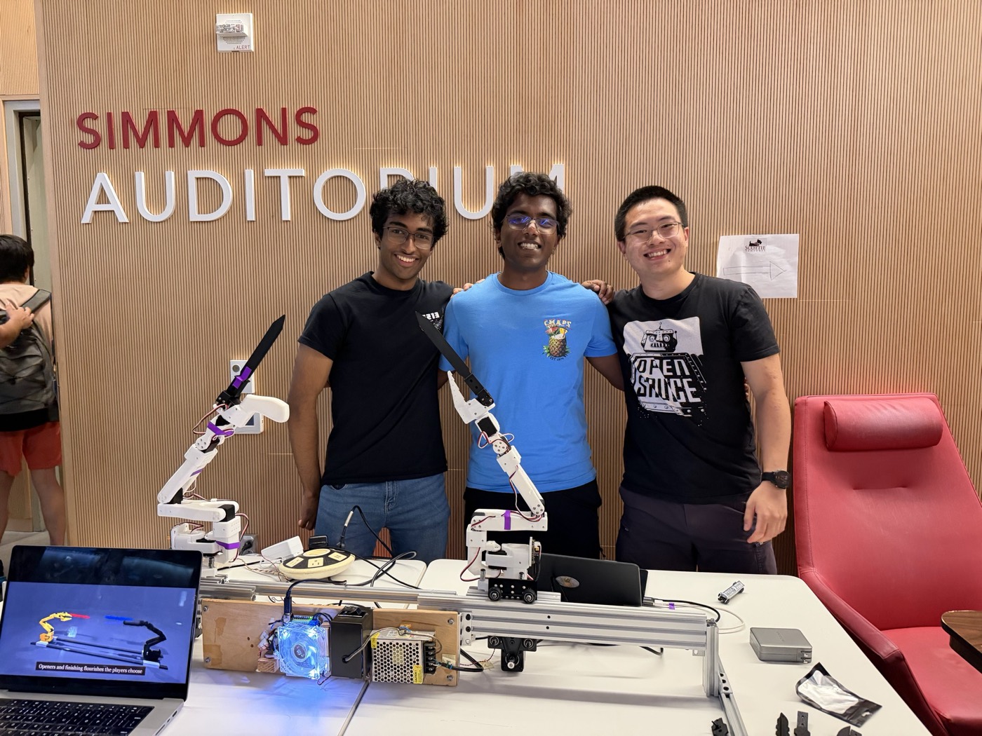 Team of three in front of the Simmons Auditorium sign, with the rig and a laptop on the table